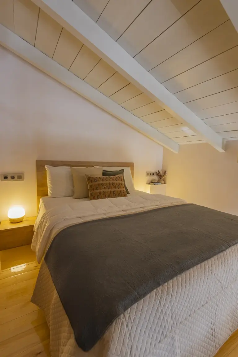 Loft bedroom of the Deluxe Studio with a sloped timber ceiling
