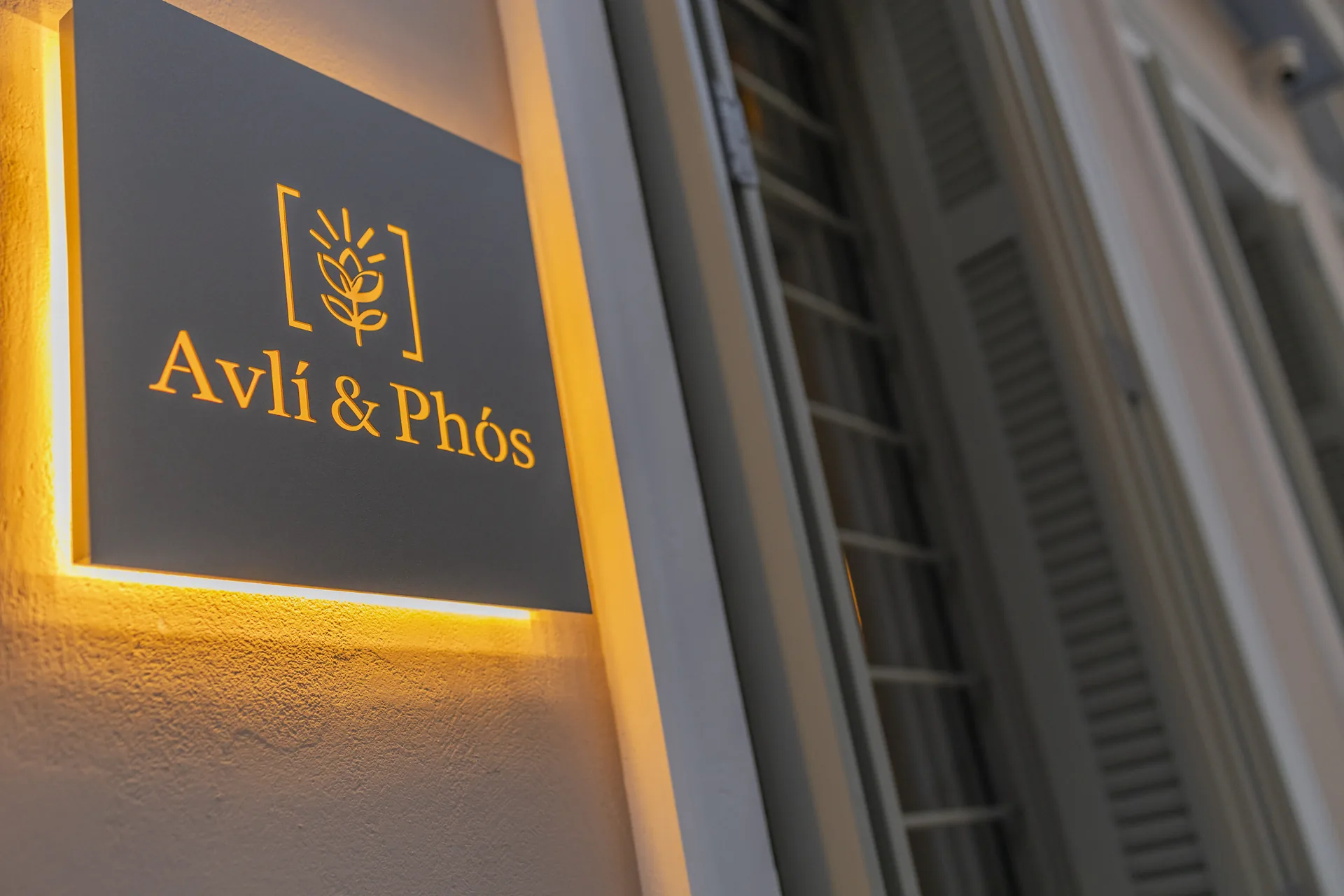 Illuminated Avlí & Phós sign on the building exterior in Thissio