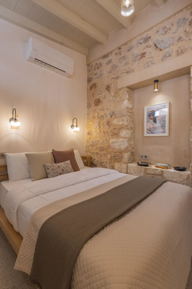 Bedroom of the Classic Studio with an exposed stone wall at Avlí & Phós