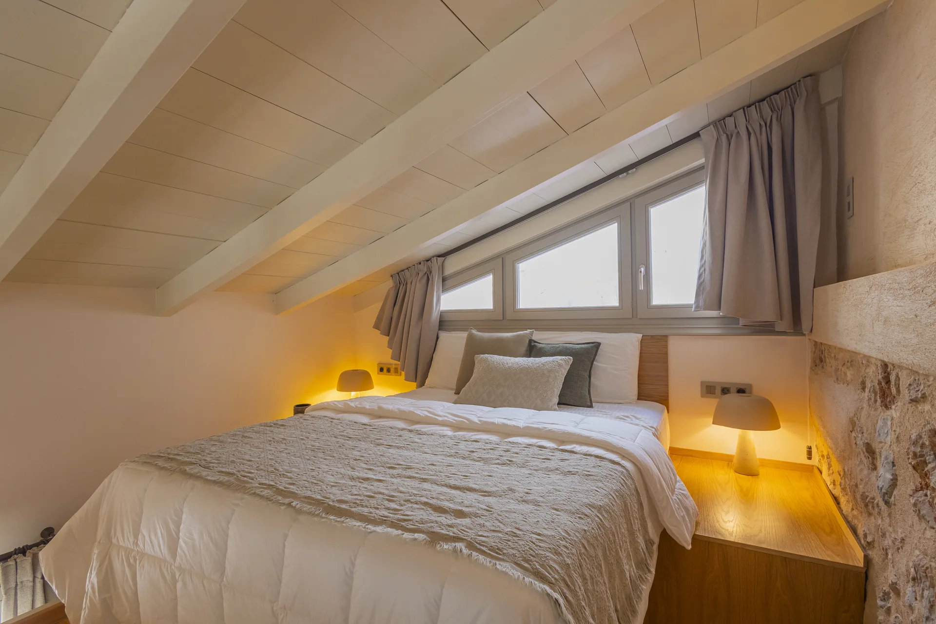 Junior Suite loft bedroom with a sloped timber ceiling and bedside lighting