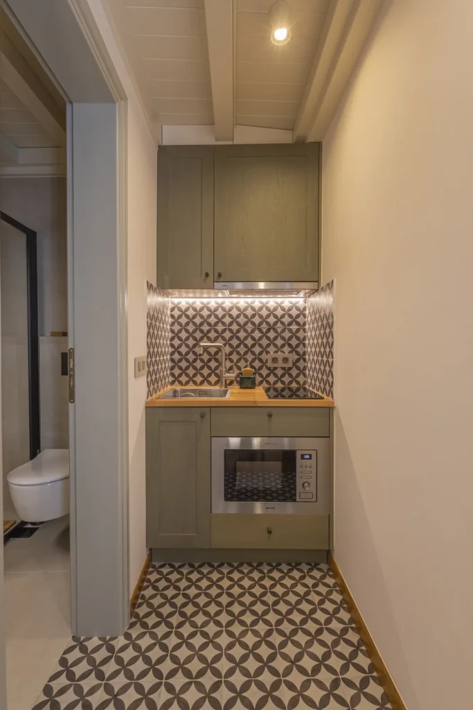 Kitchenette of the Superior Studio with patterned tiles and sage-green cabinetry