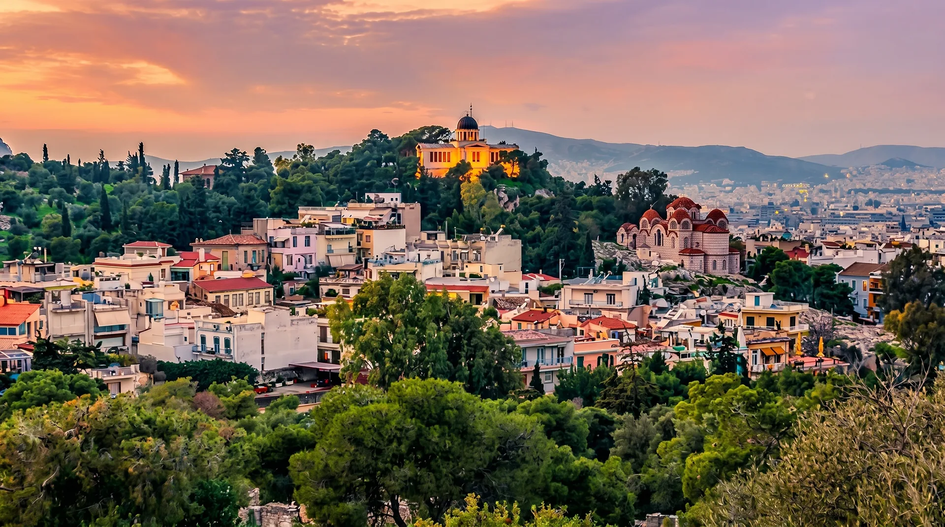 Sunset view over Thissio rooftops with the National Observatory of Athens on the hill